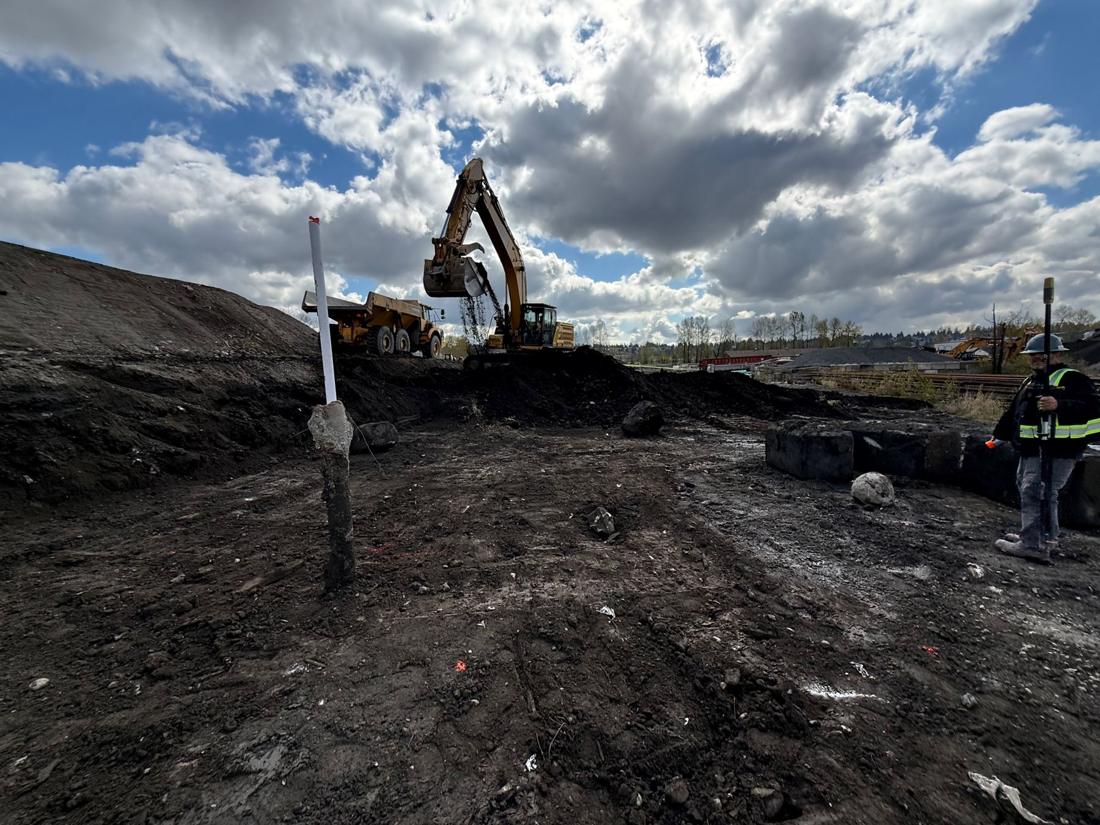 Excavator and crew working under a dramatic sky