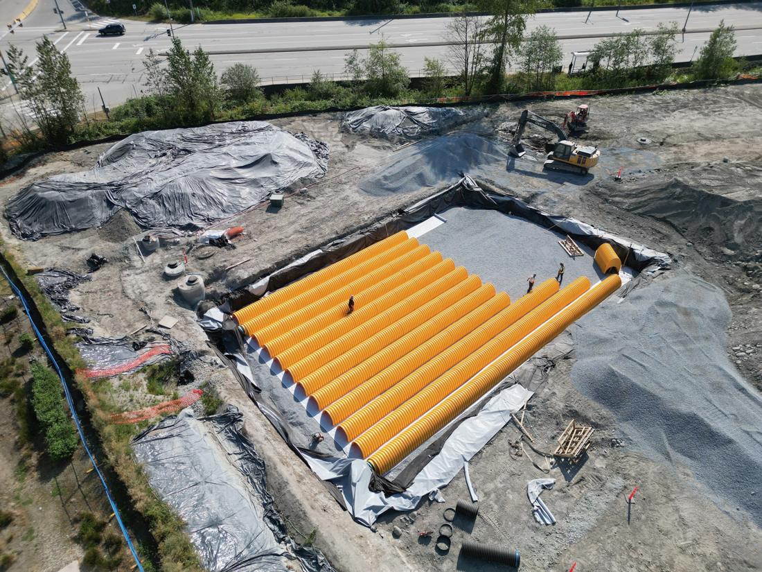 Crew setting yellow stormwater detention chambers in an excavation